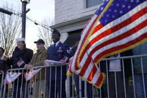 veteran smiling as parade comes by and American flag flies