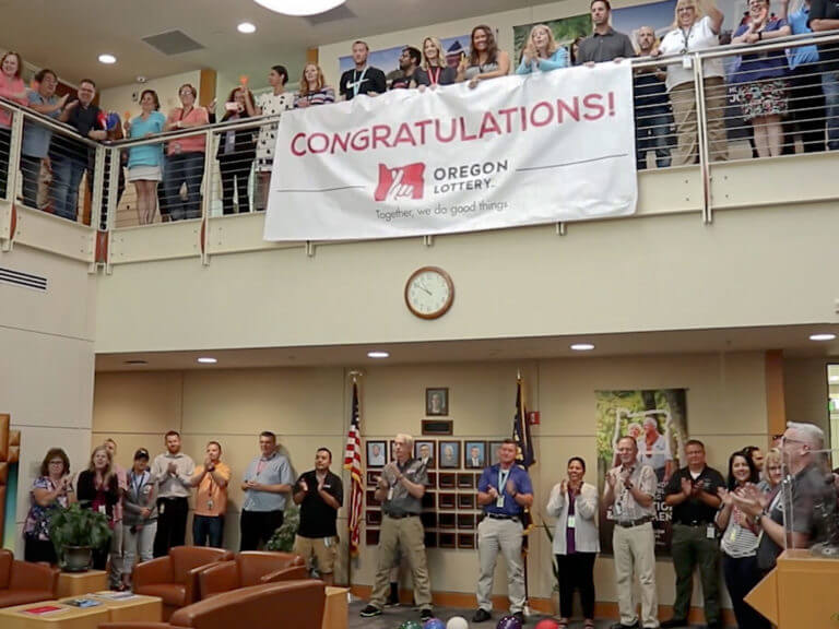 Lottery staff gathered in lobby with Congratulations banner at winner presentation