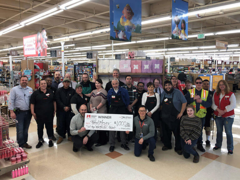 Fred Meyer employees gathered around an oversized check at a Winner Retail bonus event