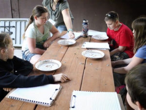 students sitting at a picnic table, doing a science experiment