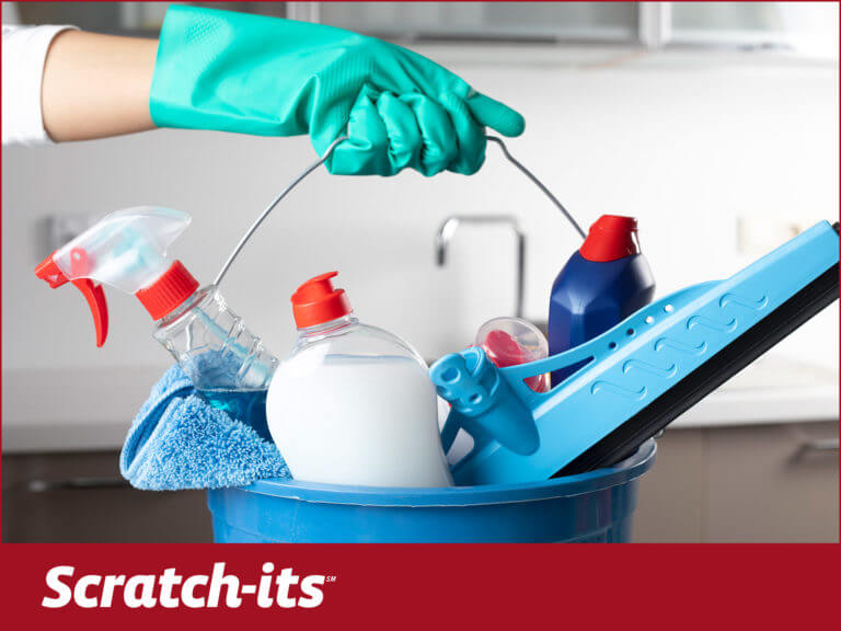 gloved hand holding bucket of cleaning supplies