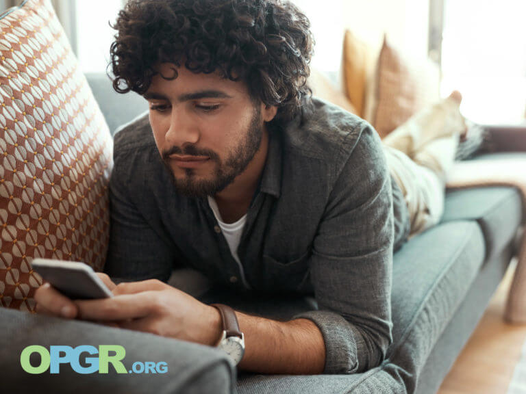 person laying on couch, looking at phone