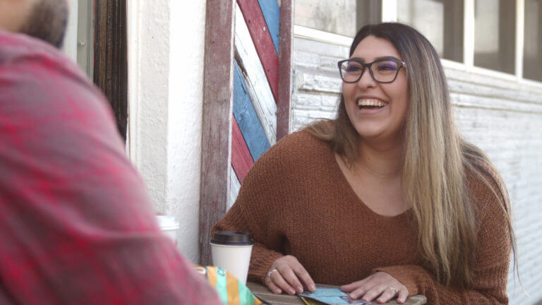 Woman with glasses sitting outside playing scratch-its