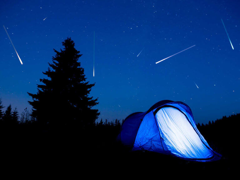Illuminated tent under a star filled night sky