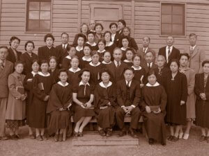 A group assembles outside a building at Minidoka