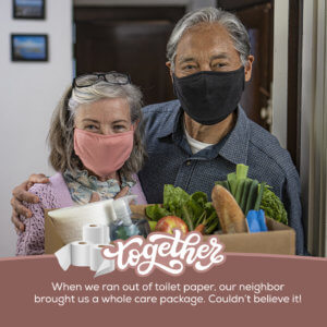 Older couple smiling behind face masks, opening the door to a box of groceries from a neighbor