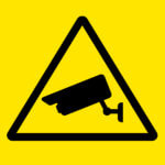 Line art of a security camera inside of a "warning" triangle