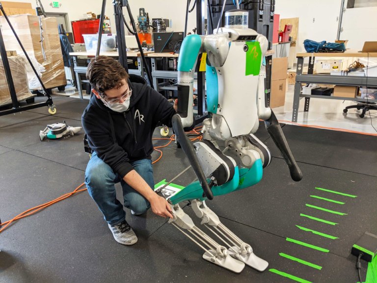 engineer makes adjustment to a tethered robot