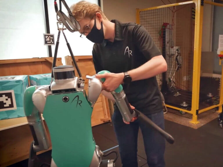A man repairs a robot in a warehouse