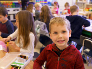 A young boy smiles in an elementary school classroom