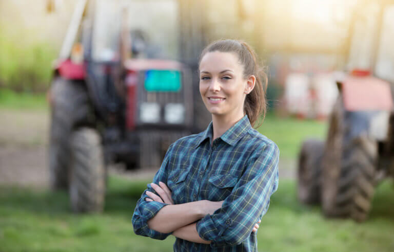 Female student poses in front of tractor