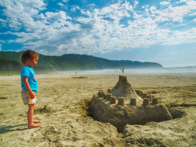 A little girl contemplates her sand castle