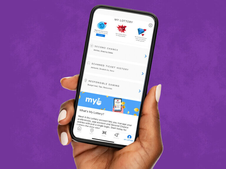 a hand holds an iphone open to the MyLottery section of the Oregon Lottery app. On the screen are menu options to view Second Chance, Scanned Ticket History, and Responsible Gaming tools.