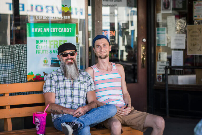 Two men sit on a bench along Main Street