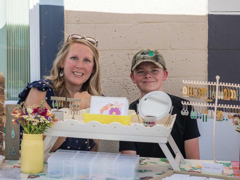 A woman and young boy man a booth at a craft fair