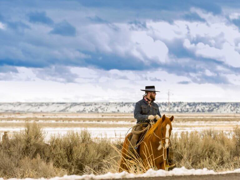 A man rides a horse across a flat landscape