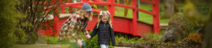 A woman and girl in front of a Japanese footbridge
