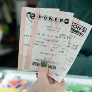 a hand with green nail polish is holding Mega Millions, Megabucks, and Powerball tickets