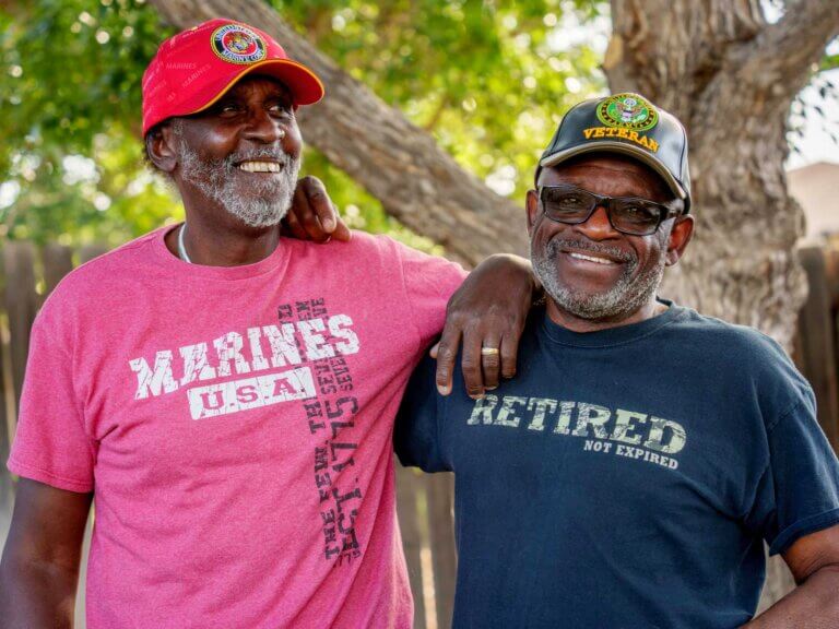 Two veterans hang out in a yard enjoying each other's company.