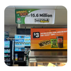 An inside shot of a typical convenience store. Hanging from the ceiling above the register is a large banner that says "Winning Ticket Sold Here! Oregon's Game Megabucks $5.6 Million"