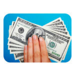 A hand with glittery manicured nails holds a spread of $100 bills